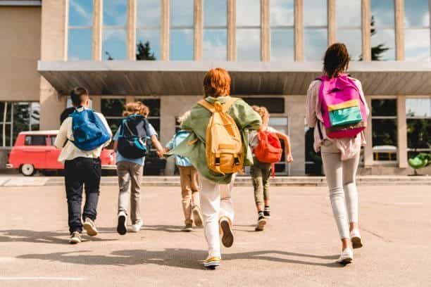 A group of children walking with backpacks in front of a building, promoting parent involvement in schools.