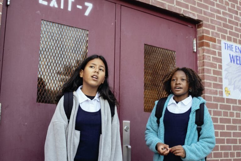 Two girls standing in front of a school door.