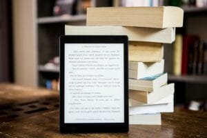 A tablet is sitting on top of a stack of books, representing the perfect tool for school marketing strategies.