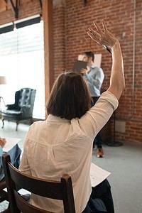 A group of people raising their hands in a meeting room during a school marketing session.