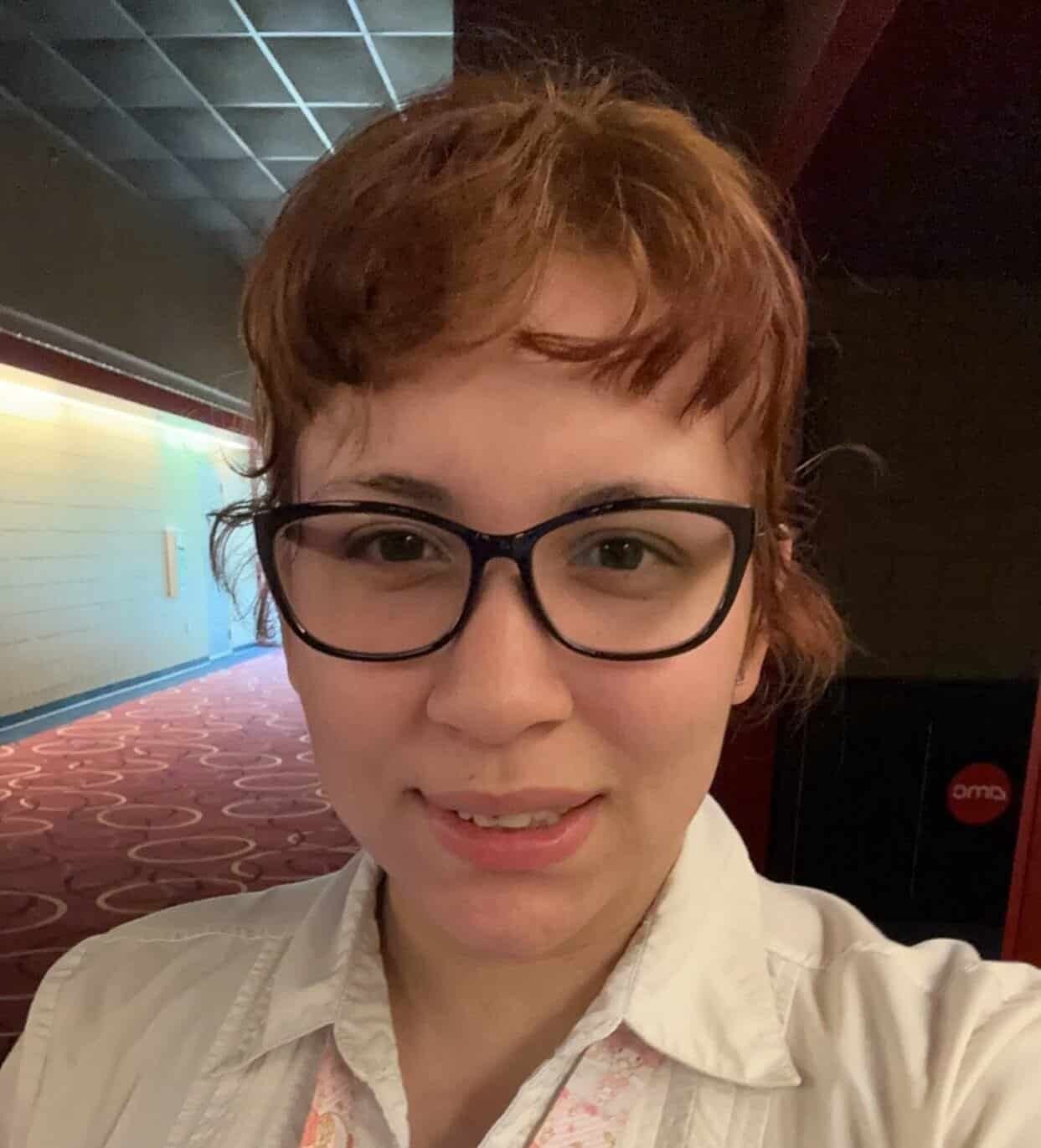 A woman wearing glasses and a white shirt.