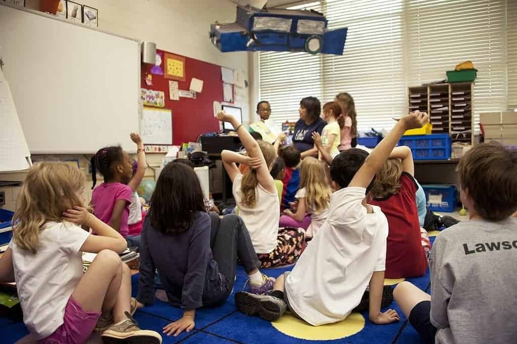 A group of children sitting on the floor in a classroom for kindergarten registration.